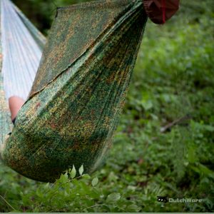 someone laying down in a chameleon hammock in the forest