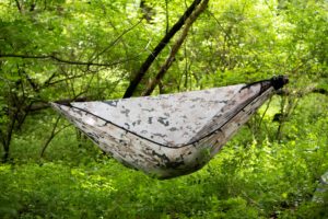 a person hanging in a chameleon hammock in the woods