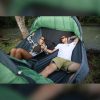 a man and a woman laying down in a double person camping hammock